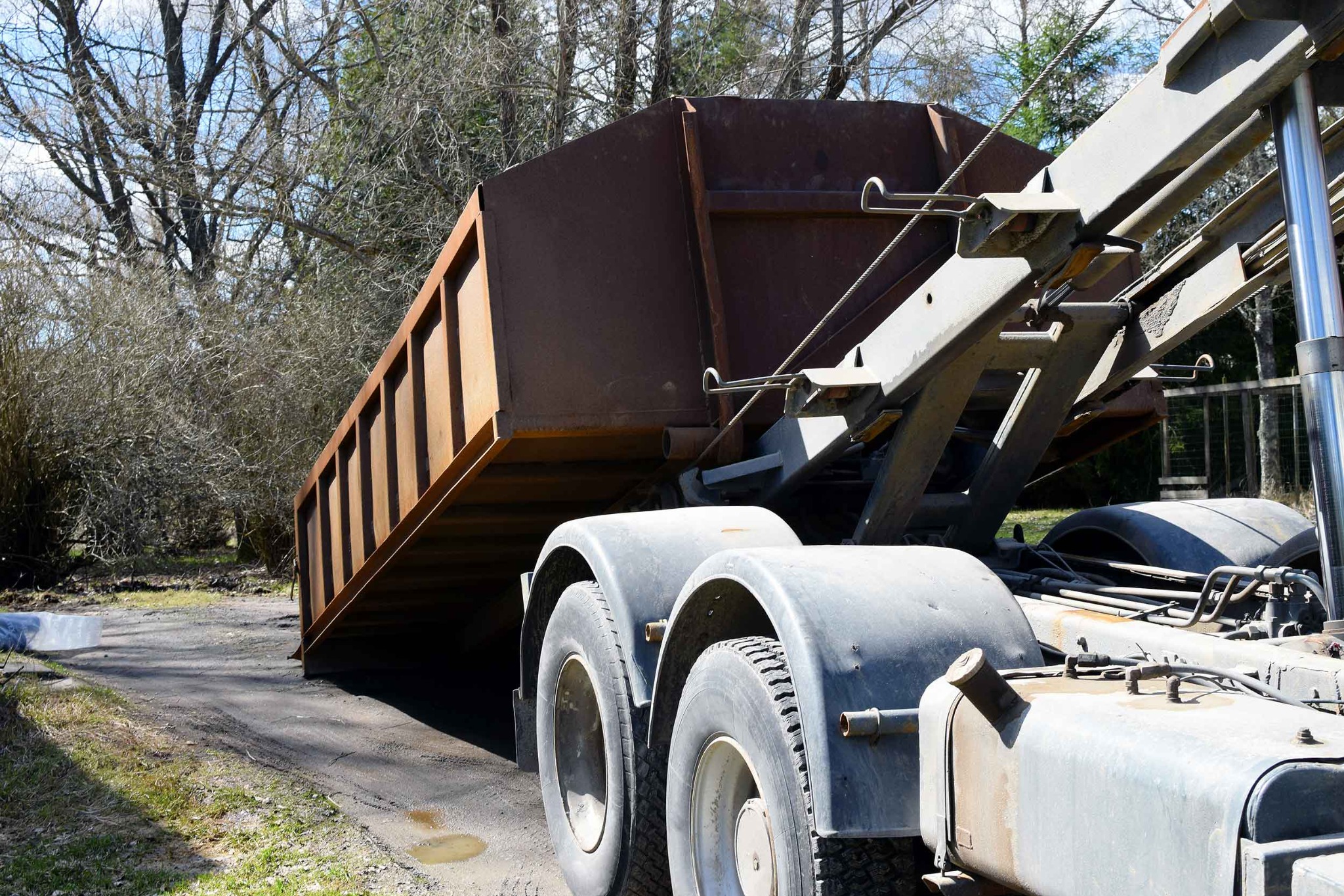 Roll-off dumpster being delivered by a hook-lift truck